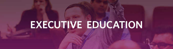 A group of people seated in a lecture or classroom setting, with the words "Executive Education" overlaying the image.