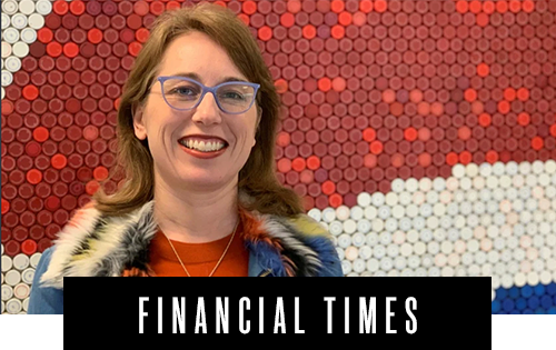 A person with glasses and a colorful jacket smiling in front of a background made of red and white circular patterns, with "Financial Times" text below.